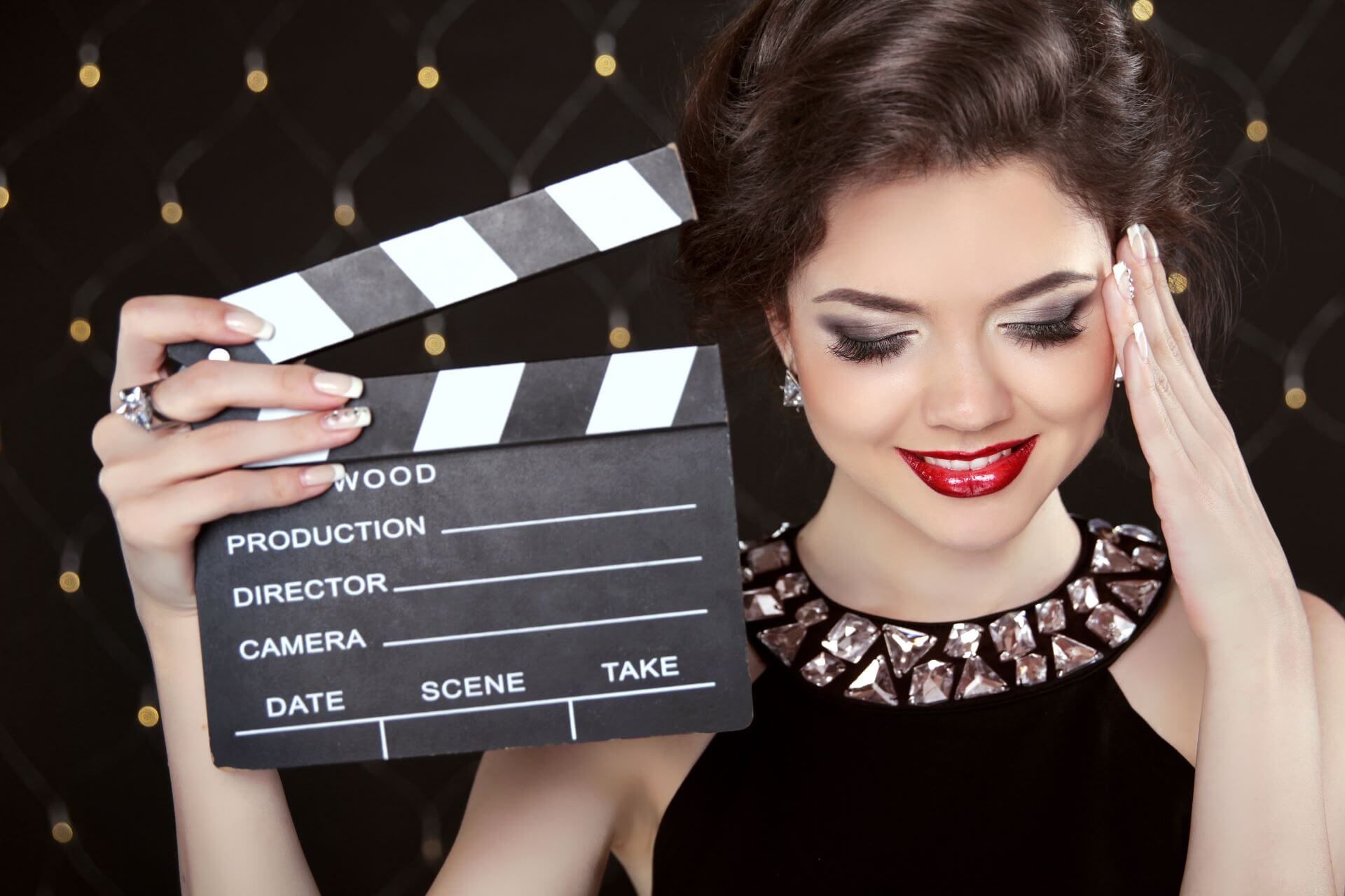 Kobieta z makijażem gwiazd trzymająca klaps filmowy