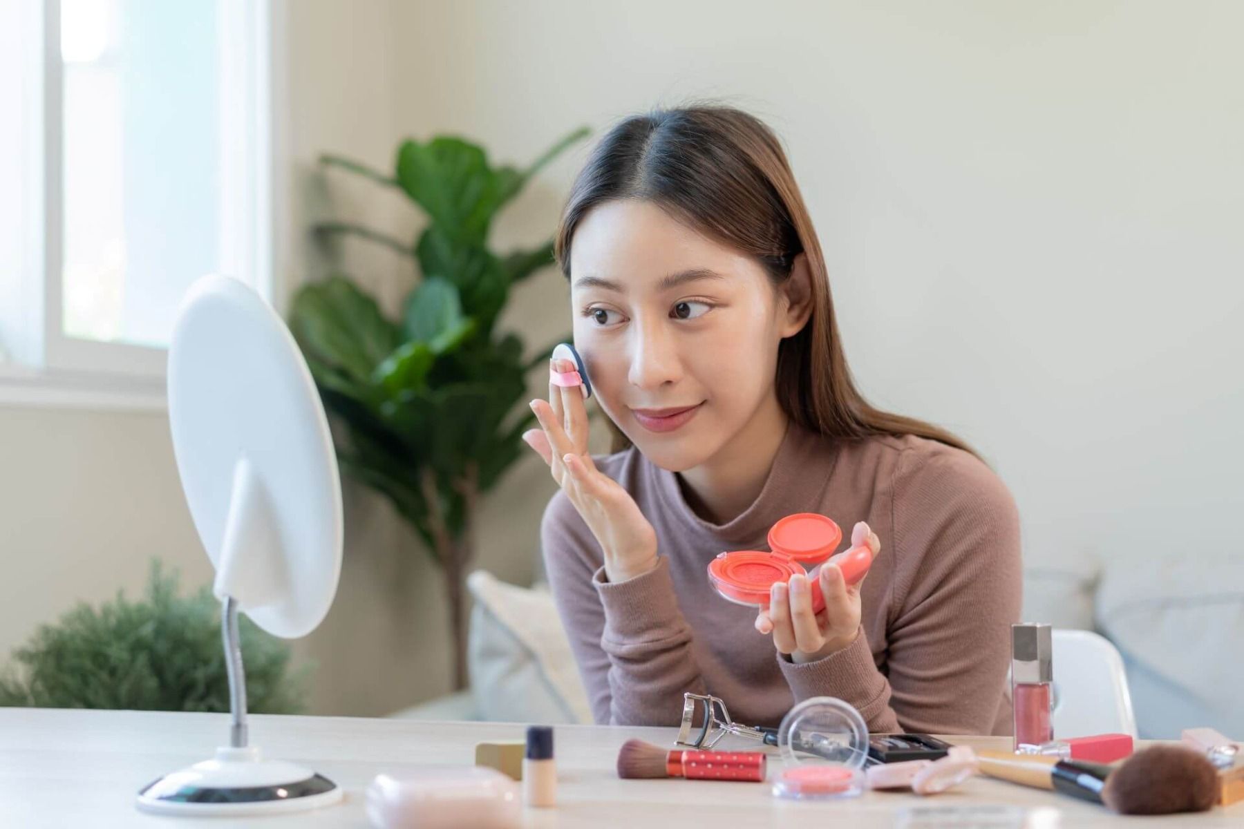 kobieta wykonuje koreański makijaż przed lusterkiem